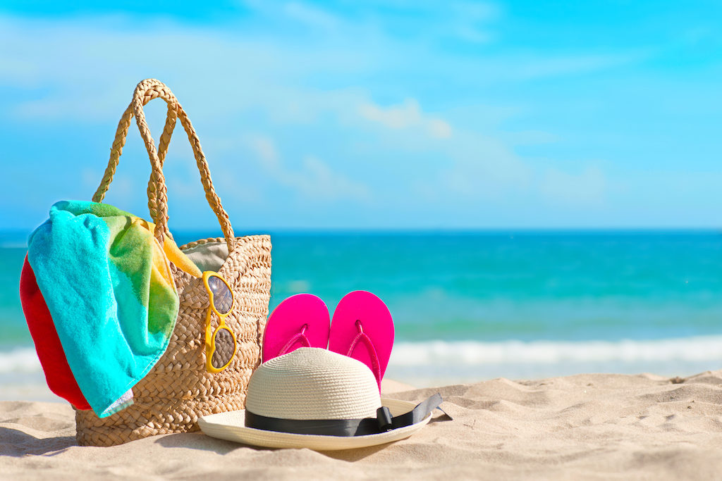 Beach bag, hat, and sandals on a beach